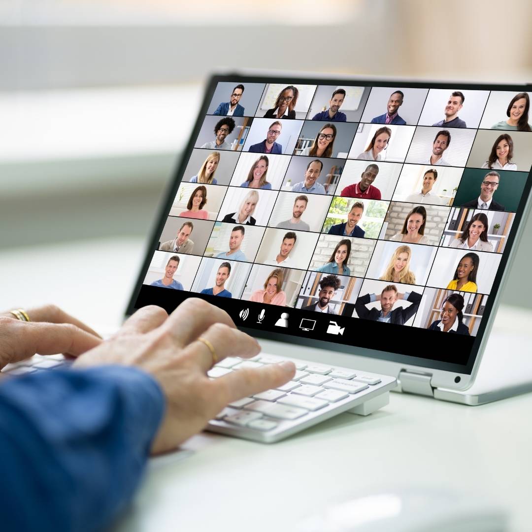 Video conference on a laptop with a grid of diverse participants in a virtual meeting.