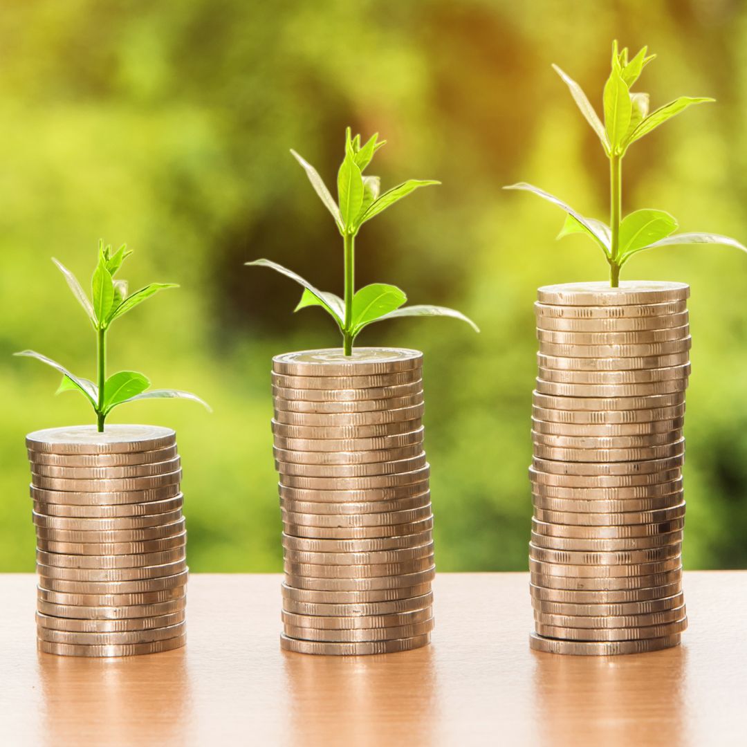 Three stacks of coins with small green sprouts on top, increasing in height from left to right, symbolizing financial growth.